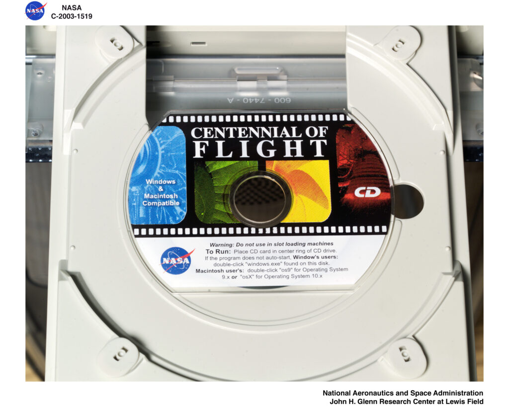 A bootable business card, which looks like a small CD with a flat top and bottom, in a CD drive. The title of the disc is "Centennial of Flight."